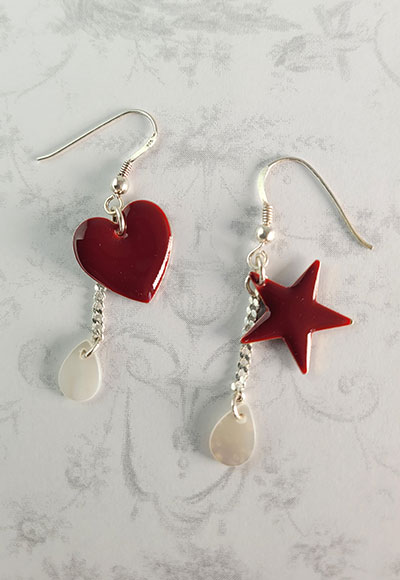 Boucles d'oreille rouge sombre, décorées d'un coeur et d'une étoile de manière asymétrique. Deux gouttes en nacre blanc se balancent au bout de ces Boucles d'oreilles originales.